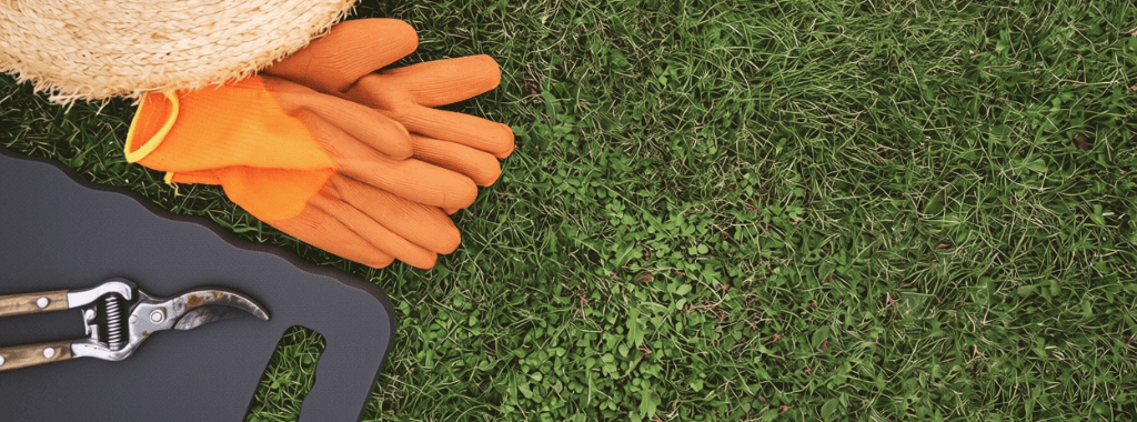 Foam kneeling pad, gardening gloves and hand tools on a lawn